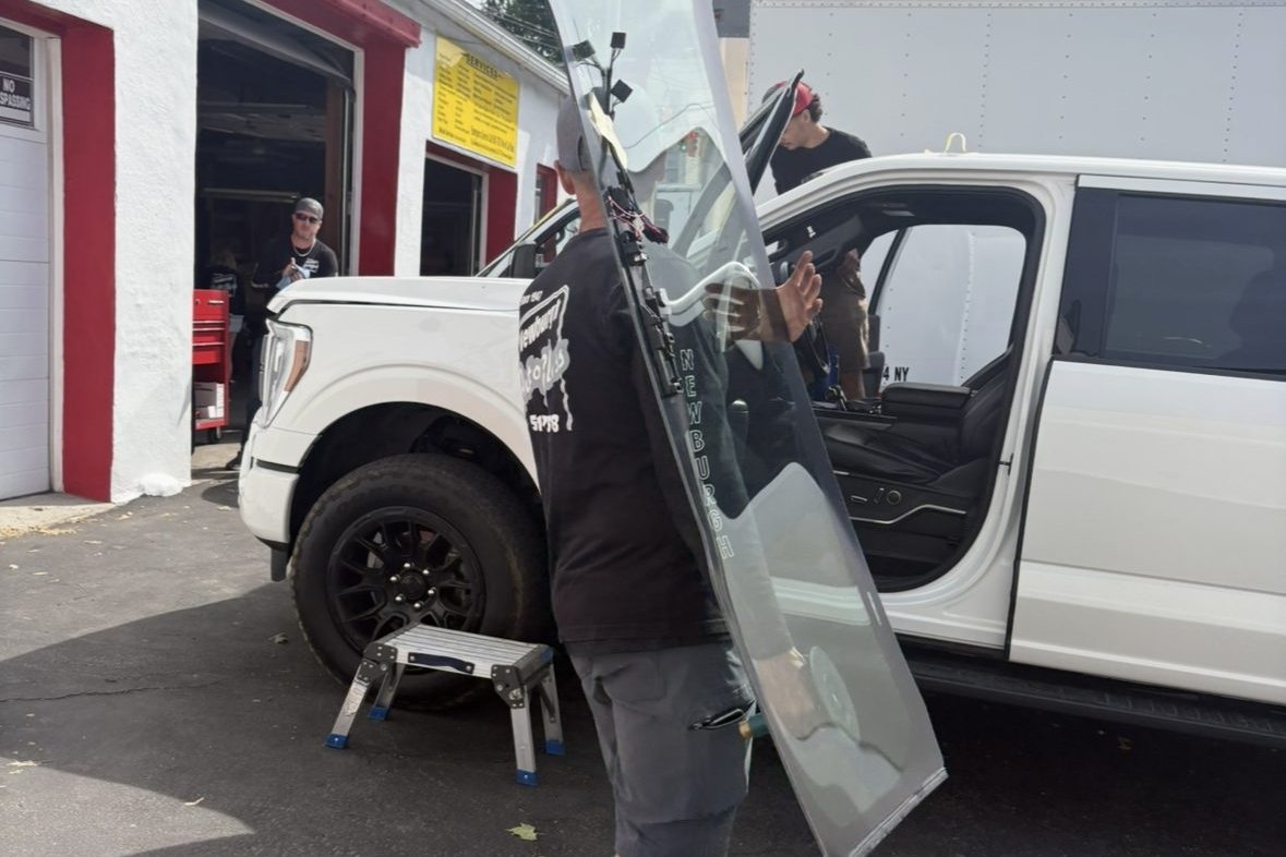 Newburgh Auto Glass technician carrying a windshield for replacement