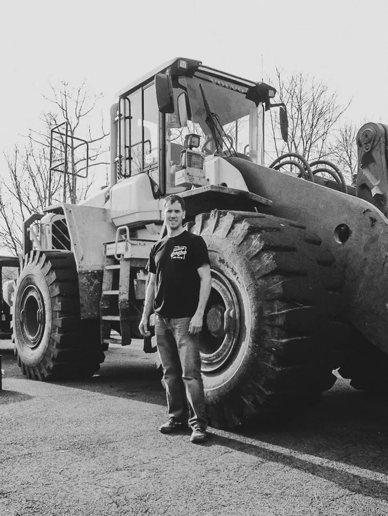 Newburgh Auto Glass technician beside a heavy equipment wheel loader