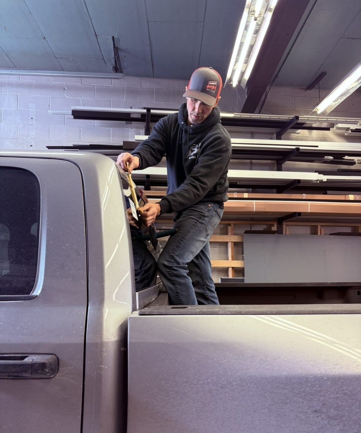 Newburgh Auto Glass technician loading auto glass onto a pickup truck in the shop